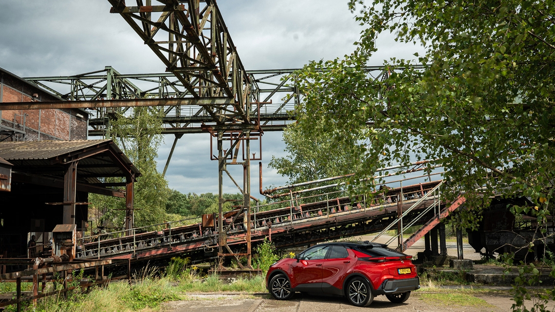 Toyota-C-HR-exterieur-linker-zijaanzicht-roodkleurig-voor-surrealistische-omgeving